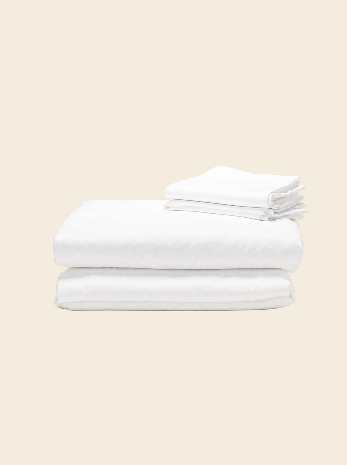 King bed sheet set in natural white, flat sheet and fitted sheet folded with pillowcases above