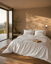 Bed made with the natural white duvet set, four pillows against warm plaster