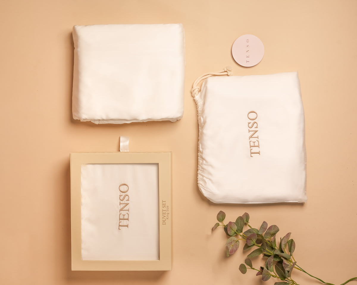 TENSO King duvet set in natural white — folded duvet cover, embroidered drawstring bag, printed presentation box and hangtag, on a champagne ground