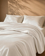 Natural white duvet cover turned back on the bed, pillows resting behind
