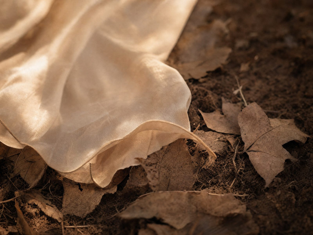 Sheer botanic cloth returning gently to leaves and soil